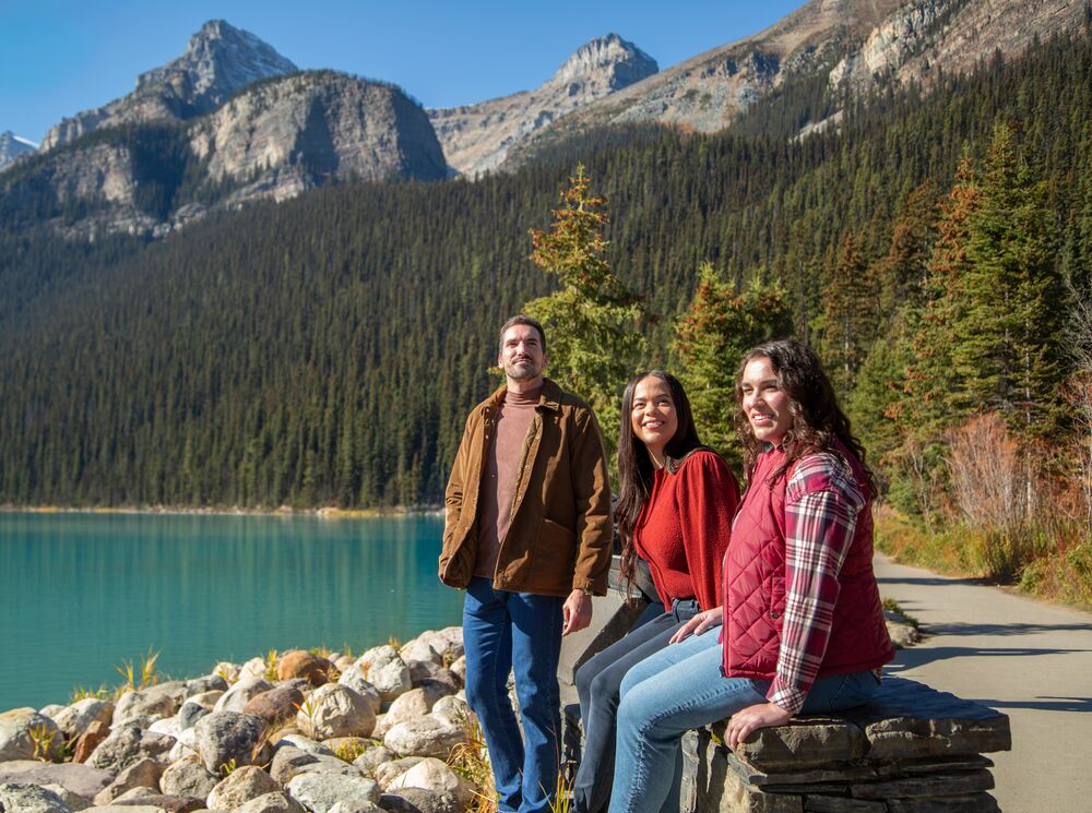 Three people walking around the Lake Louise lakeshore trail in Banff National Park