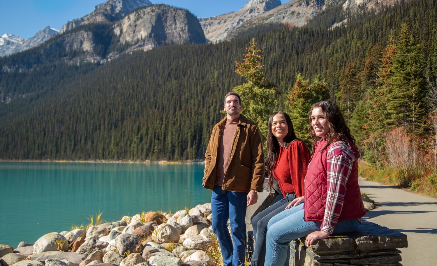 Three people walking around the Lake Louise lakeshore trail in Banff National Park