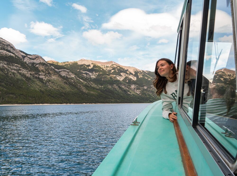 A women on The Lake Minnewanka Cruise out on Lake Minnewanka in Banff National Park with a mountain in the background.
