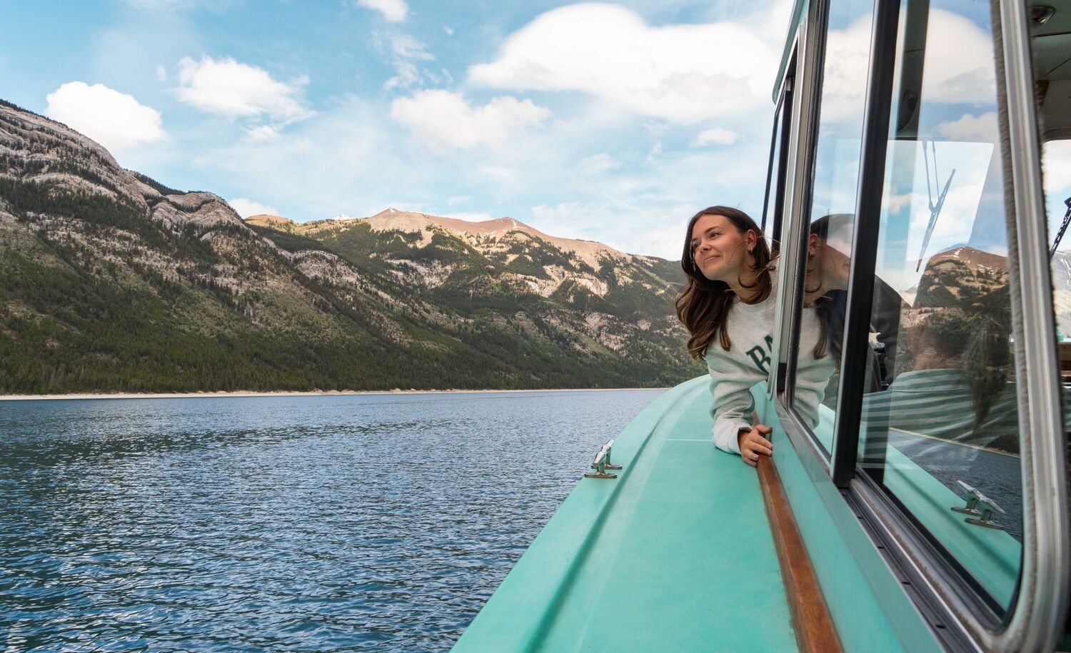 A women on The Lake Minnewanka Cruise out on Lake Minnewanka in Banff National Park with a mountain in the background.