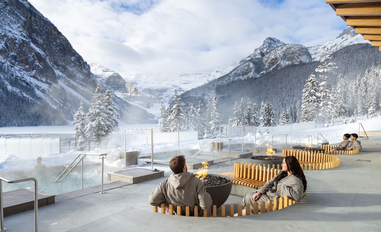A couple sitting at an outdoor fire at the Fairmont Basin Glacier Waters spa in Lake Louise