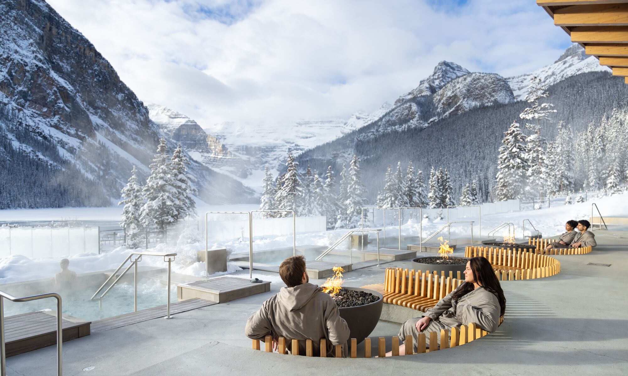 A couple sitting at an outdoor fire at the Fairmont Basin Glacier Waters spa in Lake Louise