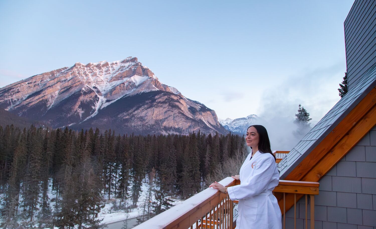 A woman stands on a balcony at the Hotel Canoe and Suites in Banff National Park in the winter.