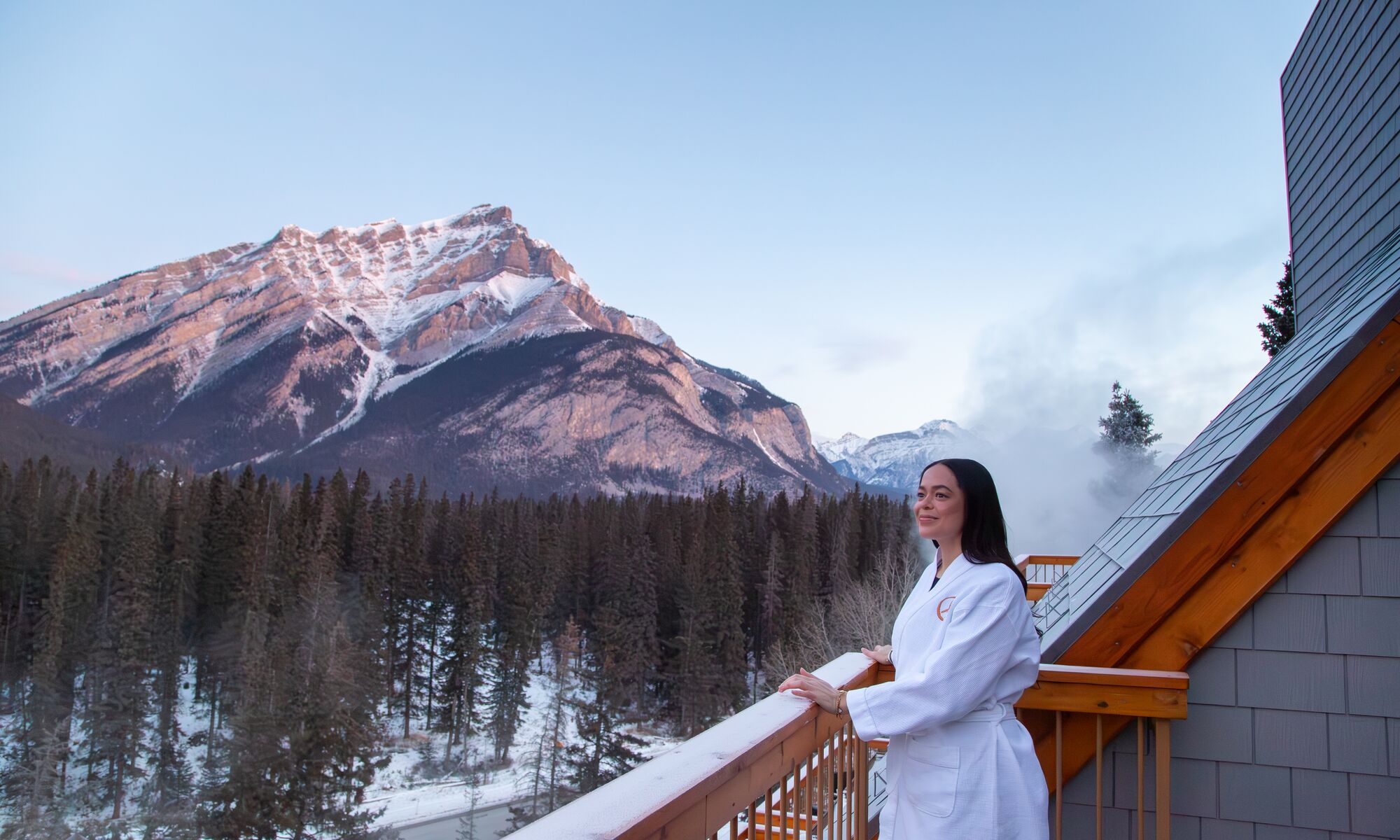 A woman stands on a balcony at the Hotel Canoe and Suites in Banff National Park in the winter.
