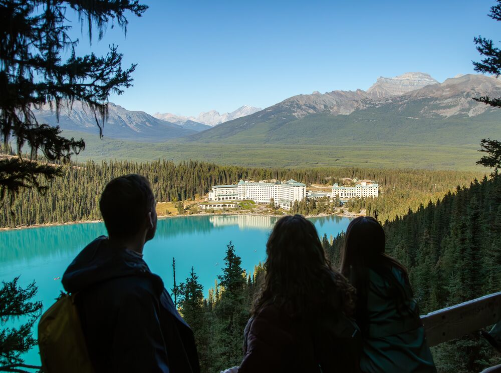 A group of people stand at Fairview Lookout in Lake Louise looking at the Chateau Lake Louise during a hike in Banff National Park.