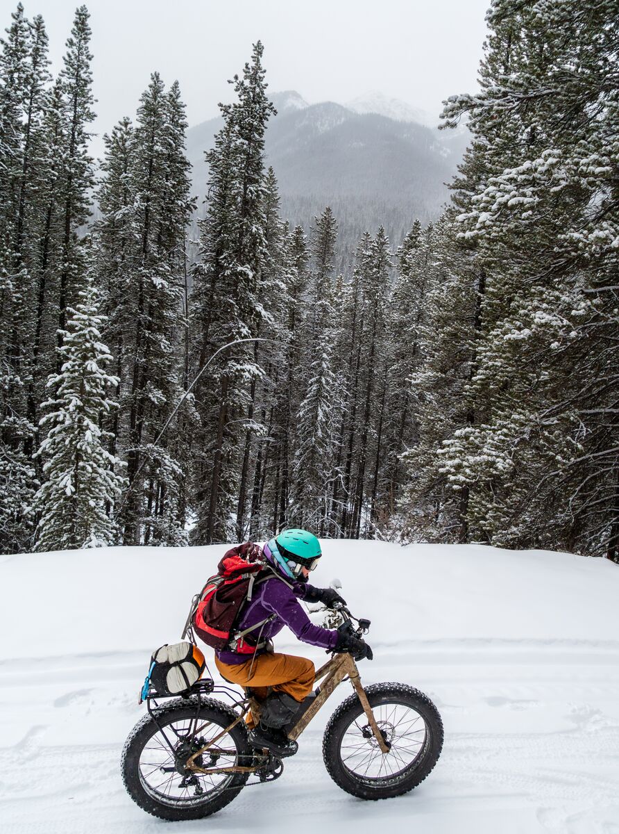 A fat bike rider in winter rolls around a corner in Banff National Park.