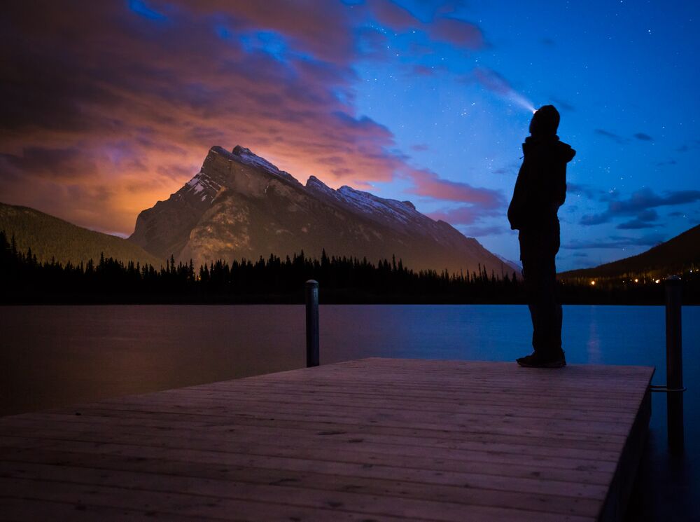 A person standing on a dock looking at the northern lights in Banff National Park