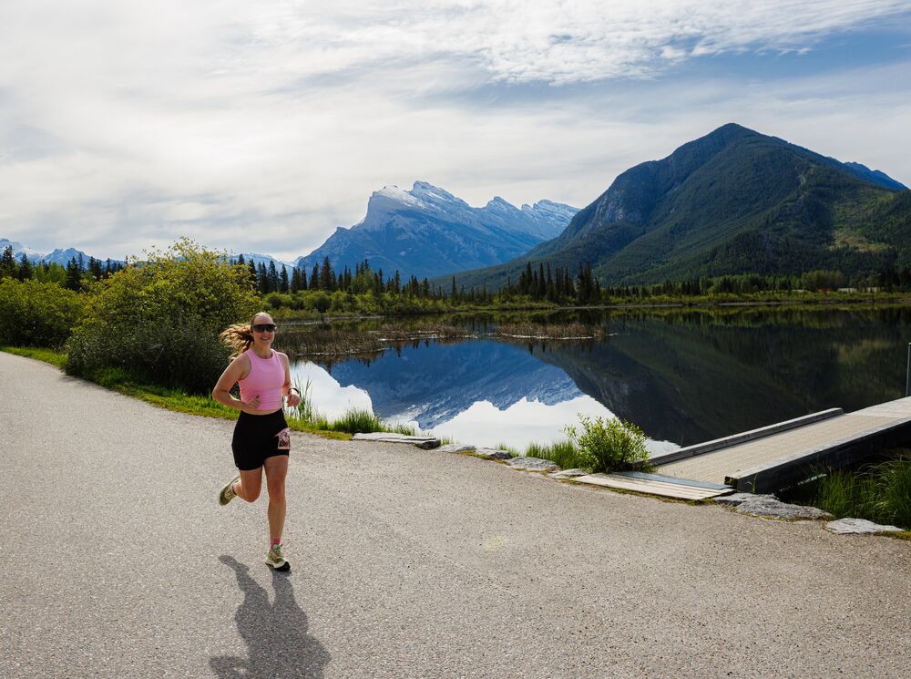 Woman running along the scenic Vermilion Lakes route during the Banff Half Marathon in Banff National Park, surrounded by mountain views and pristine wilderness at one of Canada's most iconic destination races for runners of all levels.