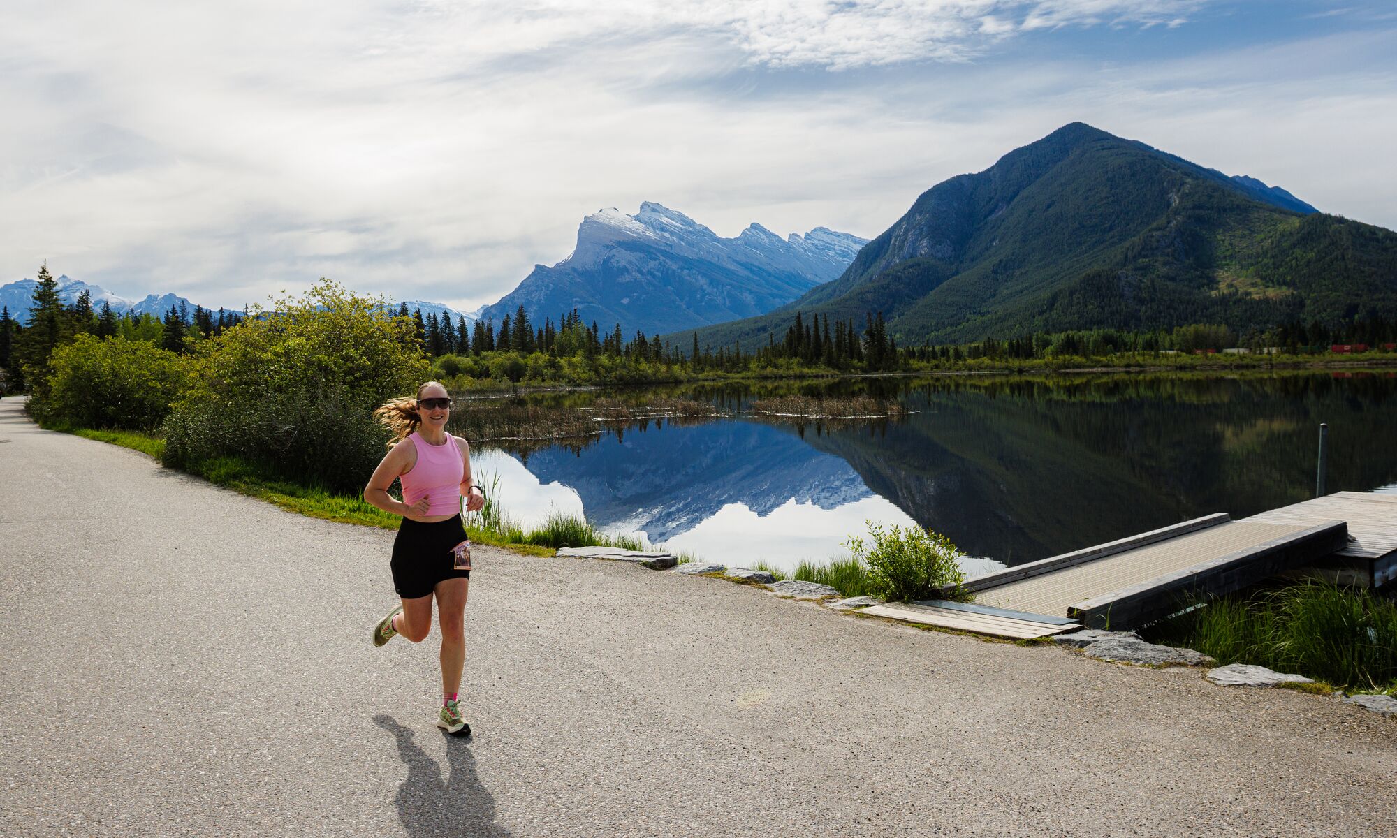 Woman running along the scenic Vermilion Lakes route during the Banff Half Marathon in Banff National Park, surrounded by mountain views and pristine wilderness at one of Canada's most iconic destination races for runners of all levels.