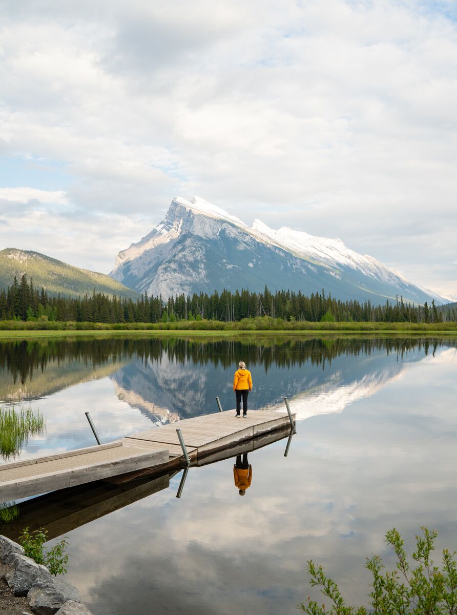 A woman stands at the end of a dock at Vermilion Lakes in the spring, a great additional activity to visiting the Banff Upper Hot Springs.
