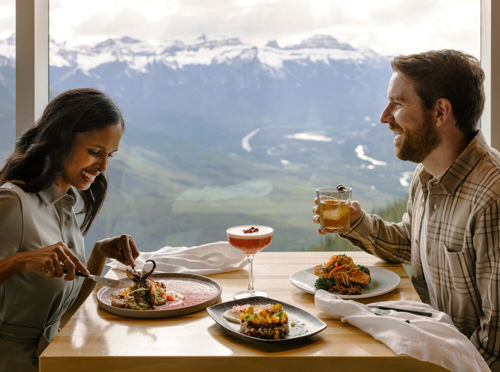 Two people enjoying a meal with mountain views at Sky Bistro at the top of Banff Gondola