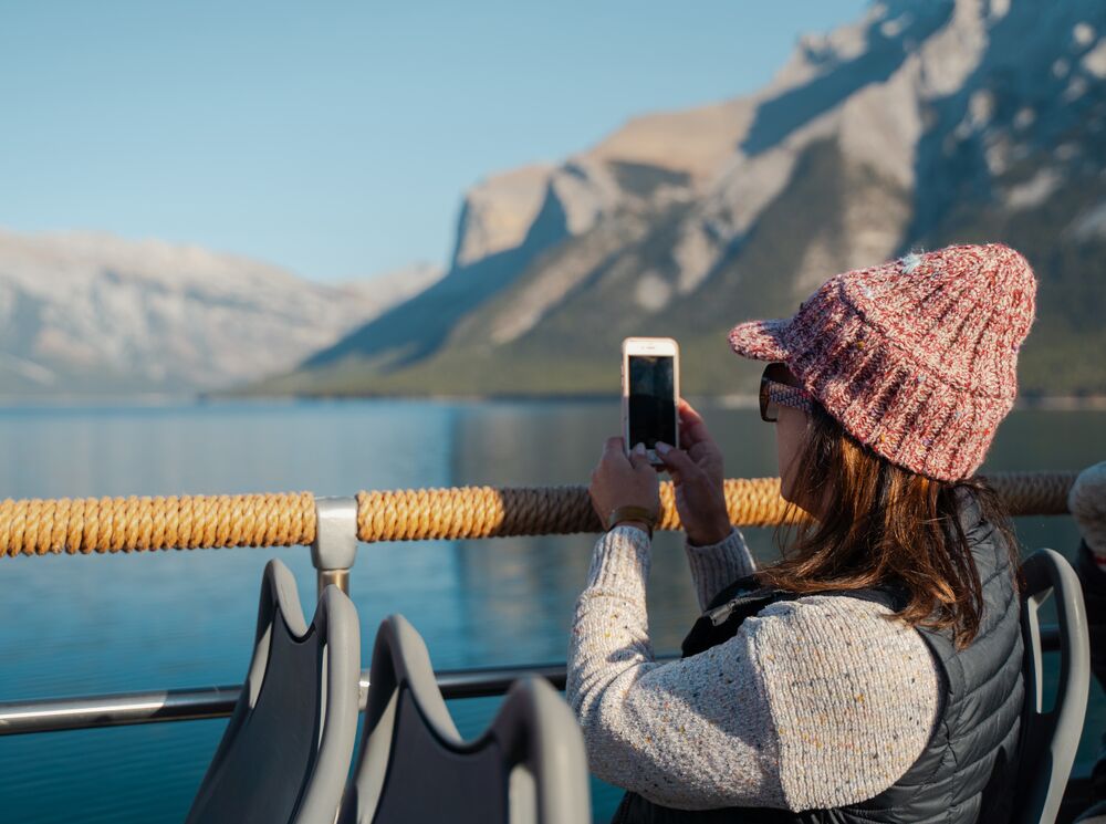 A woman takes a photo while on a tour bus at Lake Minnewanka in Banff National Park.