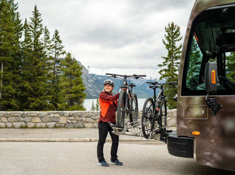 A Roam Transit bus stops along the Minnewanka Loop in Banff National Park as a passenger unloads her bike