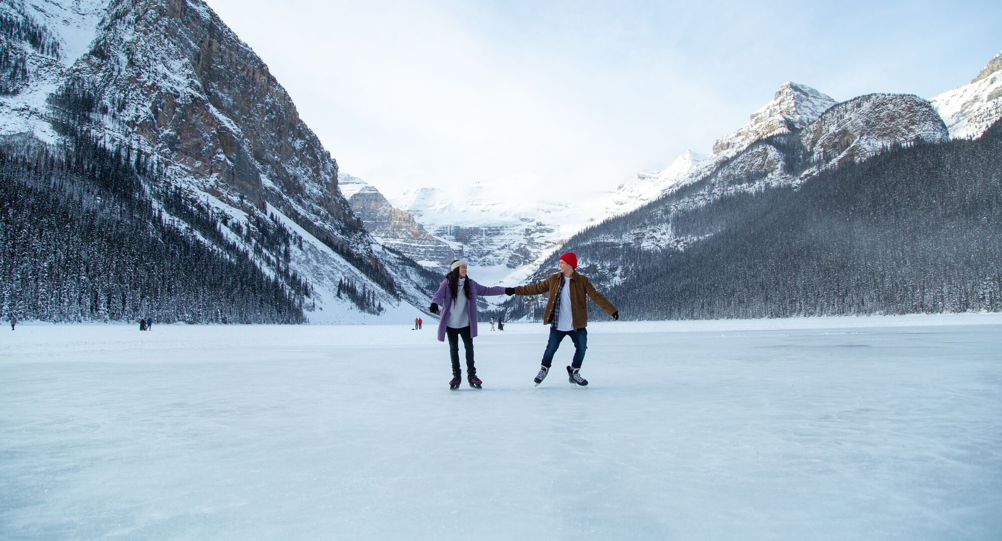Two people skating on the ice rink on Lake Louise with the Victoria Glacier in the background