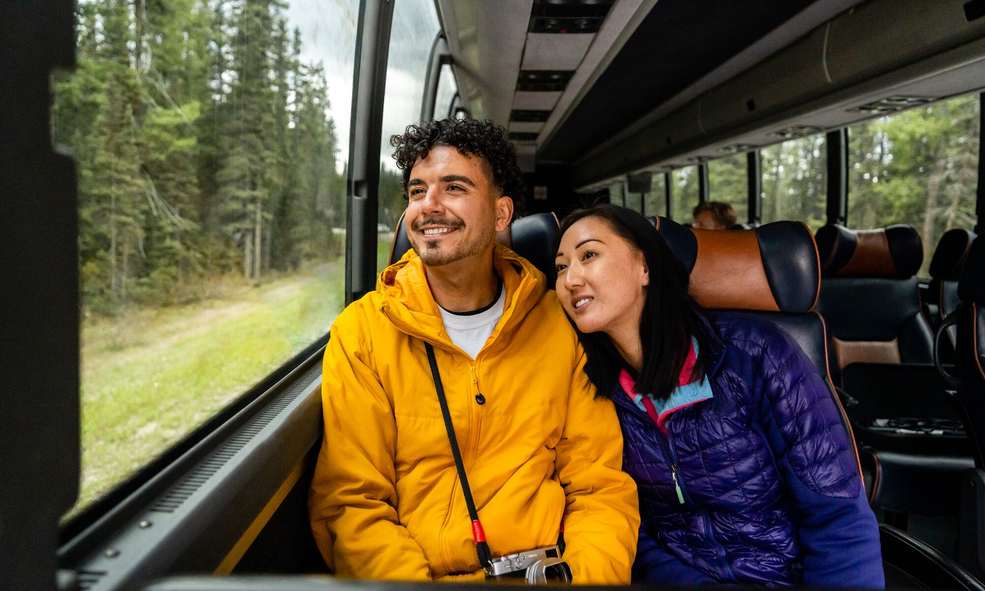 Two people look out the window on a Parks Canada shuttle to Moraine Lake.