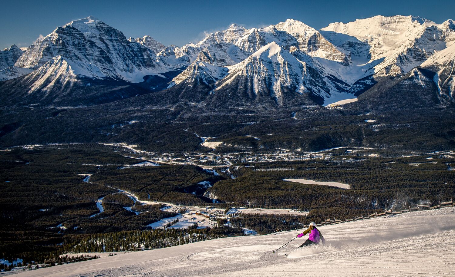 A skier heads down a run at the Lake Louise Ski Resort in Banff National Park with Lake Louise in the background.