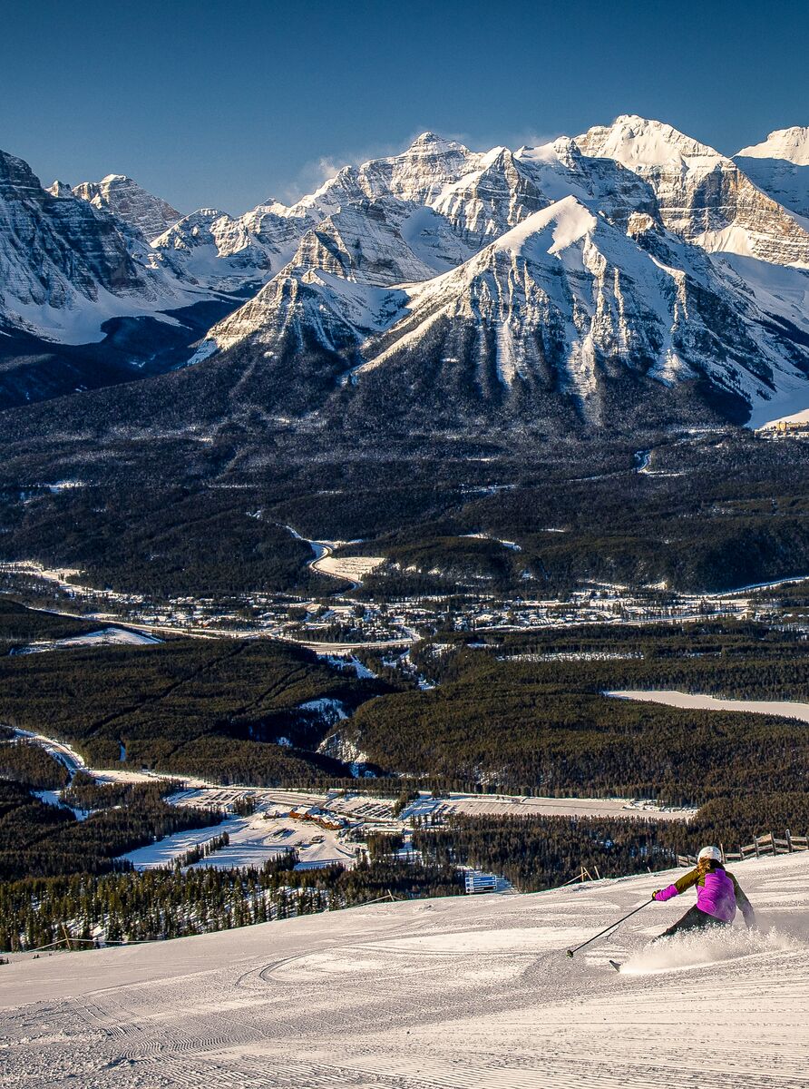 A skier heads down a run at the Lake Louise Ski Resort in Banff National Park with Lake Louise in the background.