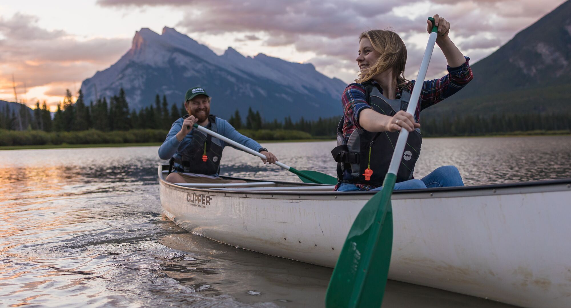 Two people paddling in a canoe on Vermilion Lakes at sunrise