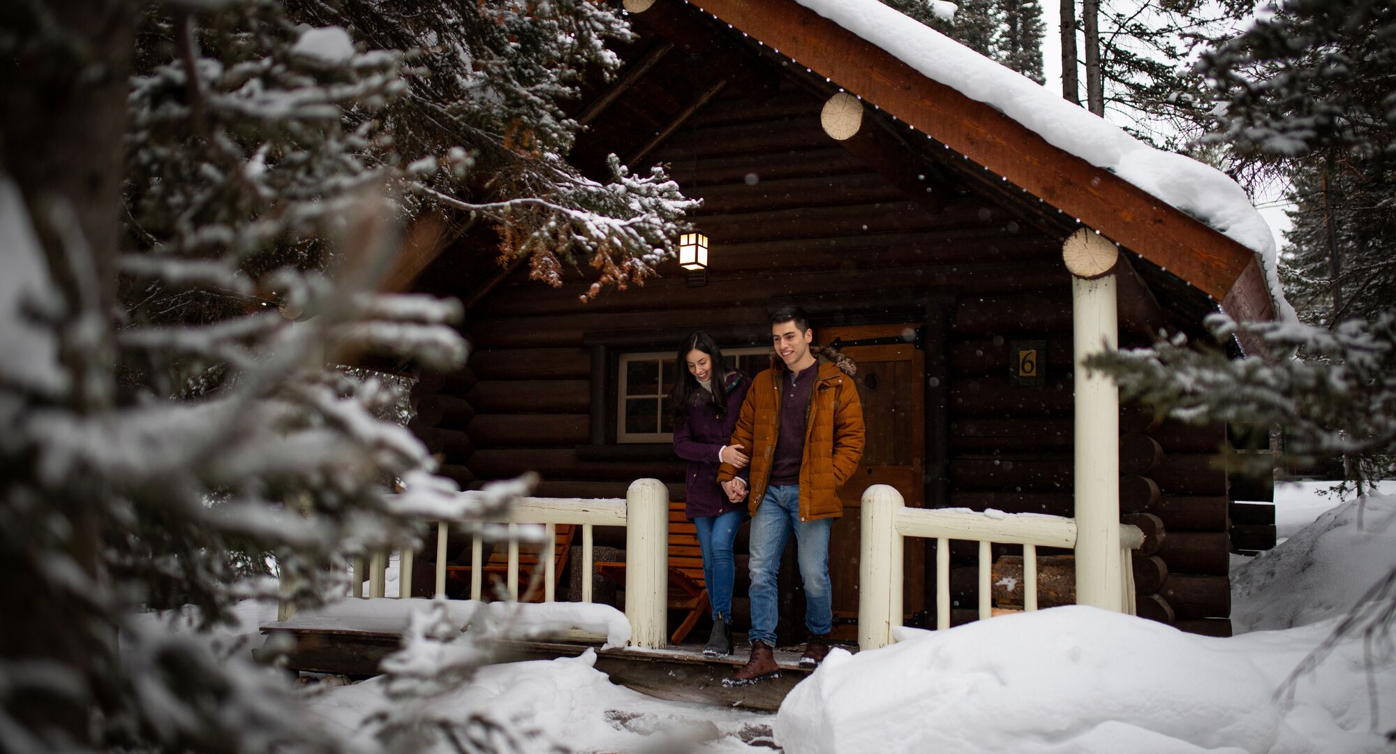 A cozy cabin in the woods in Banff National Park in the winter with snow falling.