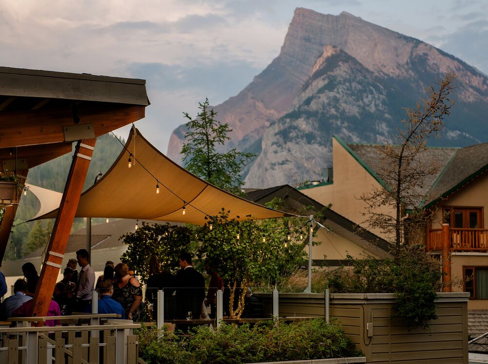 People enjoy a sunset on the roof of The Bison with views of Mt. Rundle in the distance