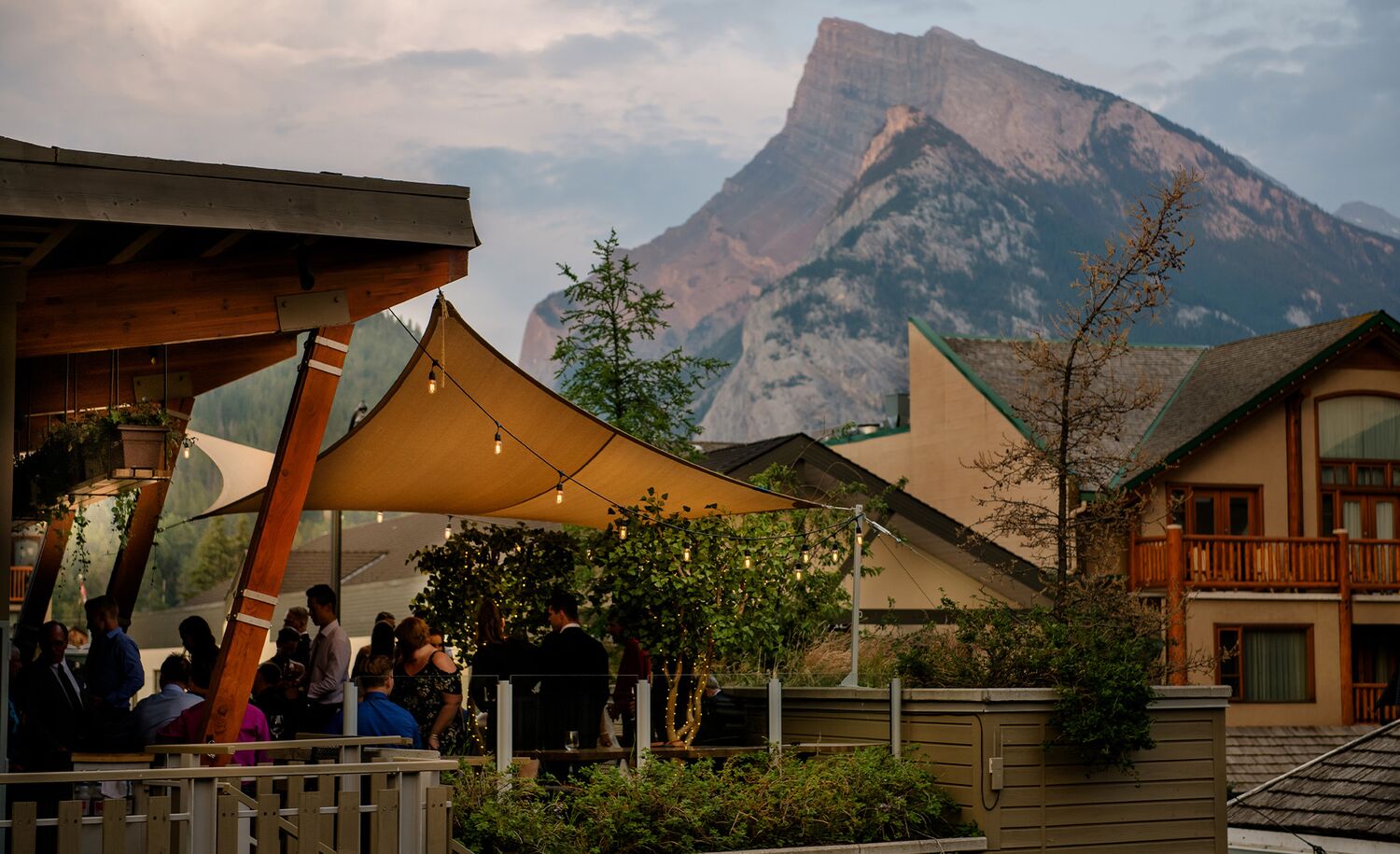 People enjoy a sunset on the roof of The Bison with views of Mt. Rundle in the distance