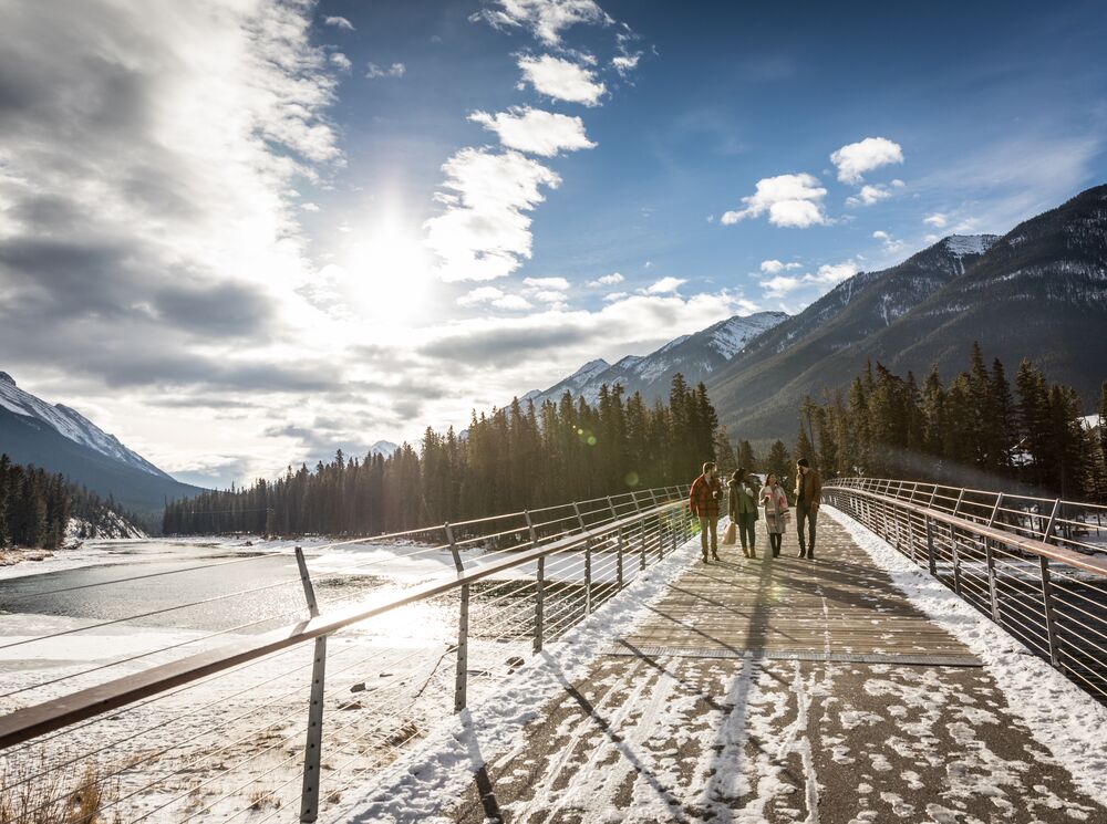 Friends cross the Banff Pedestrian Bridge on the Bow River Trail on the way to Bow Falls