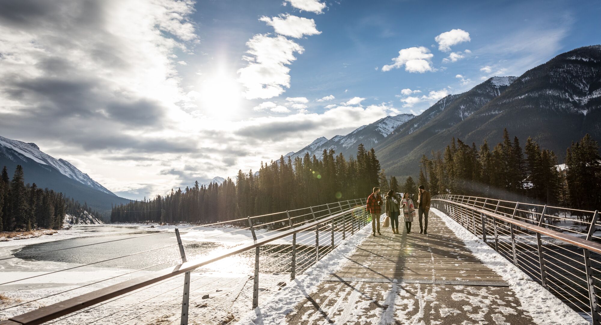 Friends cross the Banff Pedestrian Bridge on the Bow River Trail on the way to Bow Falls