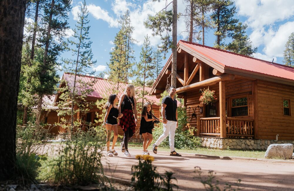 A family walks through the trees in summer at Baker Creek by Basecamp near Lake Louise in Banff National Park.