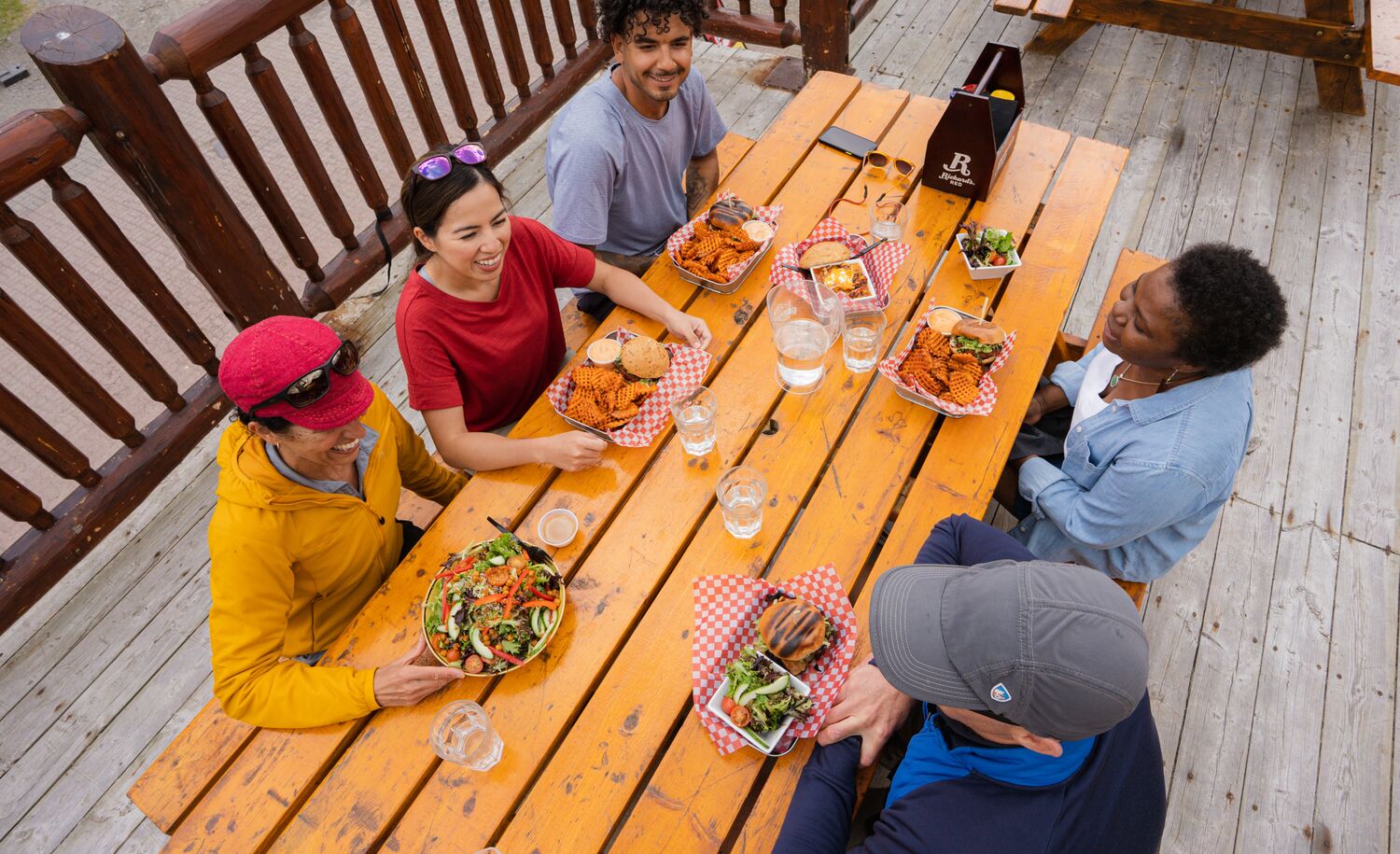A group of friends enjoys food and drinks on a patio at Sunshine ski resort in Banff National Park. 
