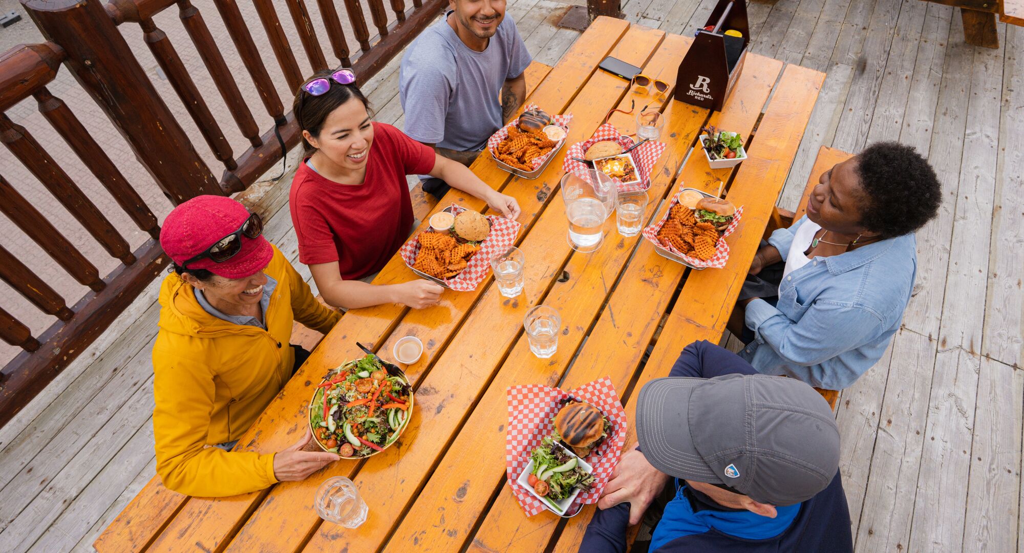 A group of friends enjoys food and drinks on a patio at Sunshine ski resort in Banff National Park. 