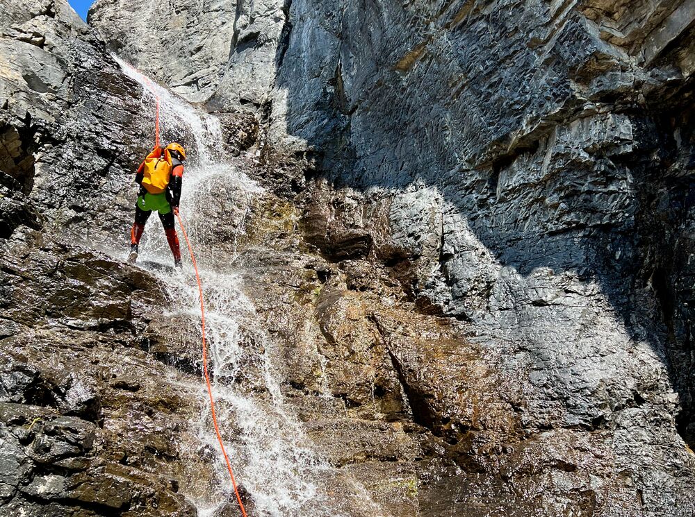 A person repelling down a waterfall in a canyon with Bow Valley Canyon Tours