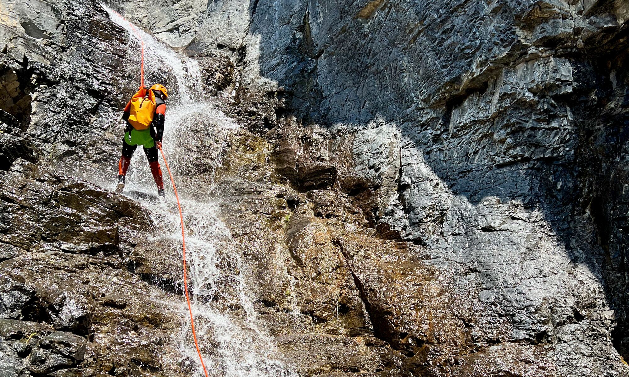 A person repelling down a waterfall in a canyon with Bow Valley Canyon Tours