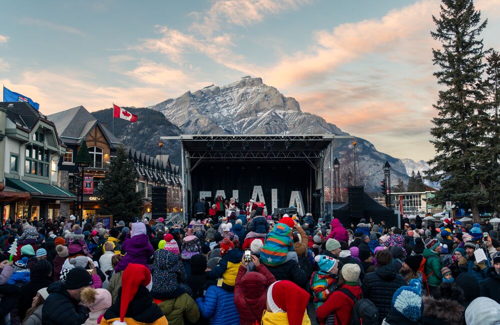 A family watches christmas themed stilt walkers in Banff for the Santa Claus Celebration of Lights