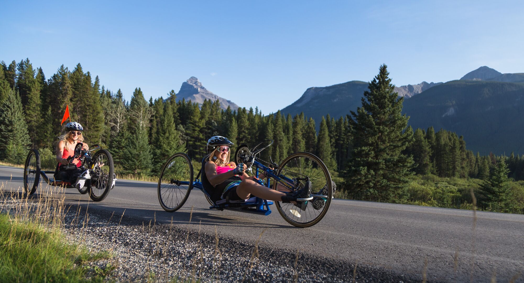 Two people cycling the Bow Valley Parkway on adaptive bikes in the summer time