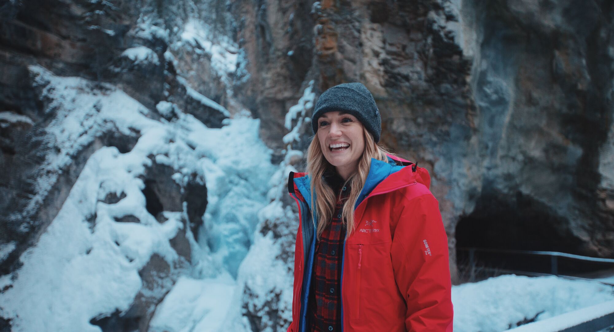 A person standing in front of the Lower Falls on the Johnston Canyon trail in the winter