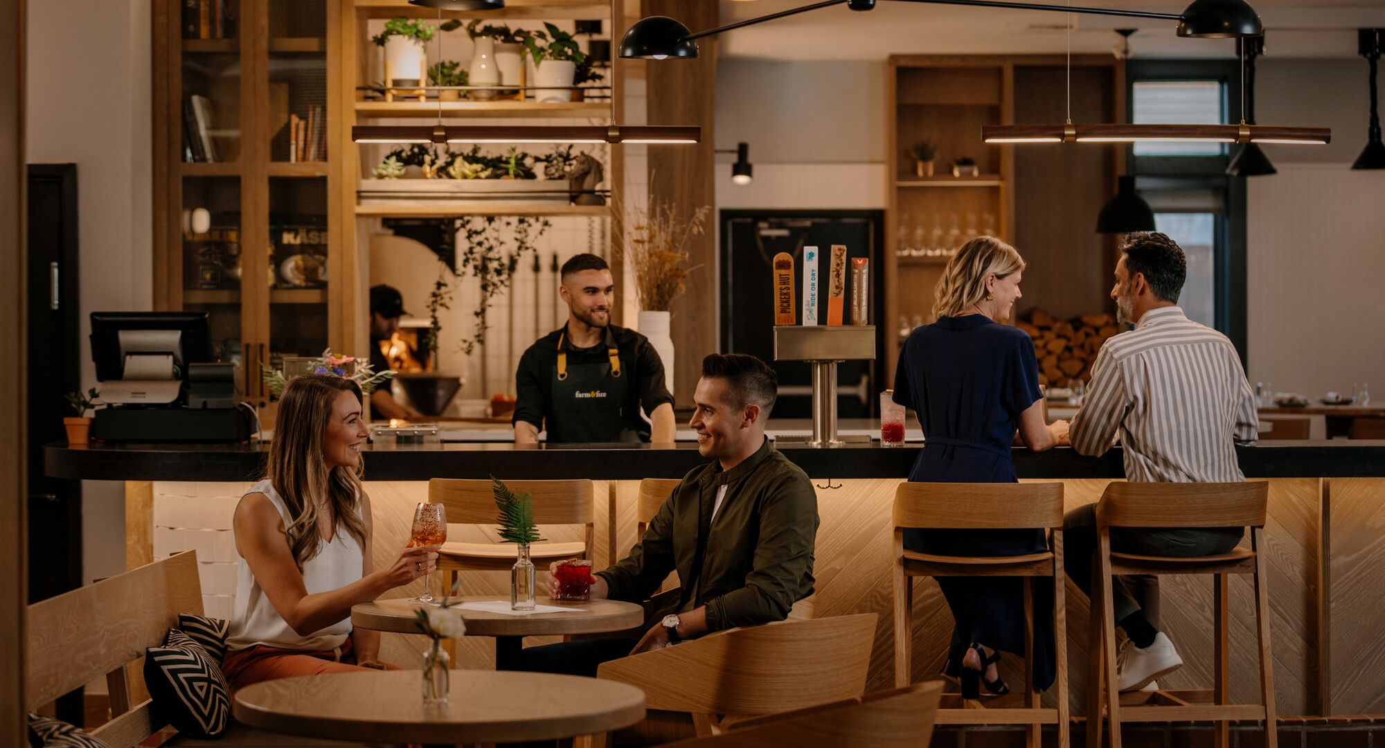 Couples sit and enjoy drinks at the various tables and at the bar at Farm & Fire in Banff National Park