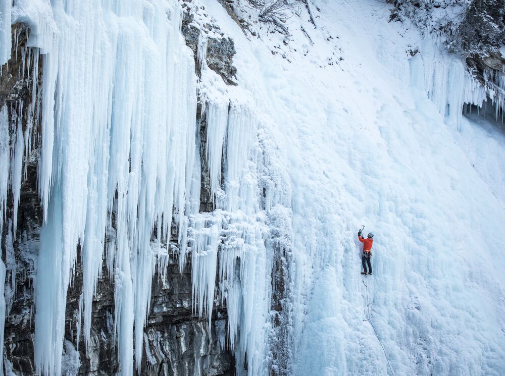 An Ice climber climbs up the frozen waterfall in Johnston Canyon on a crisp winter day.