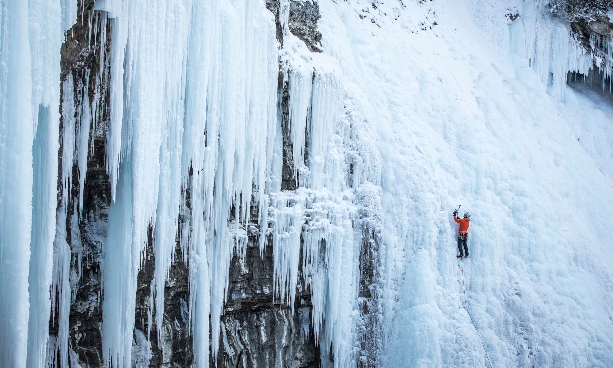 An Ice climber climbs up the frozen waterfall in Johnston Canyon on a crisp winter day.