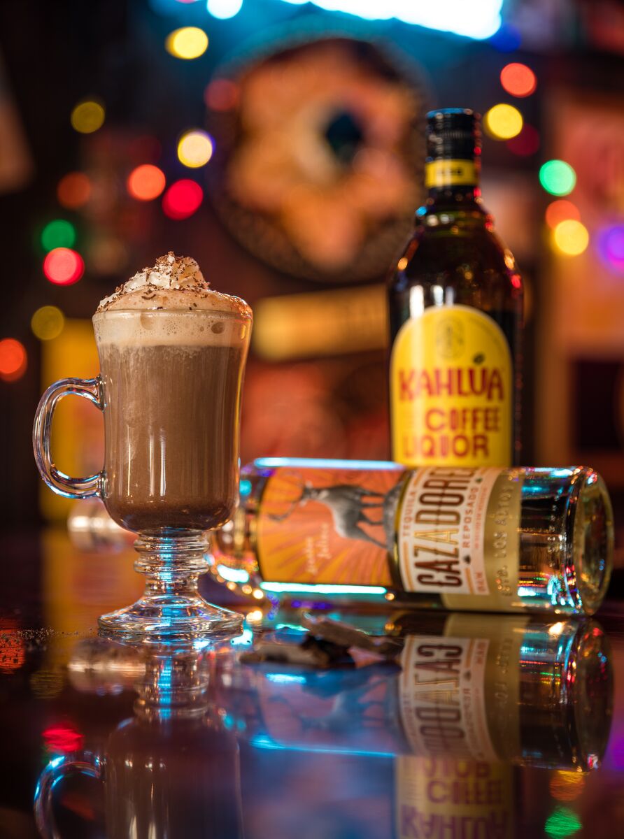 A boozy hot chocolate on a counter with liqueur bottles at Magpie & Stump.