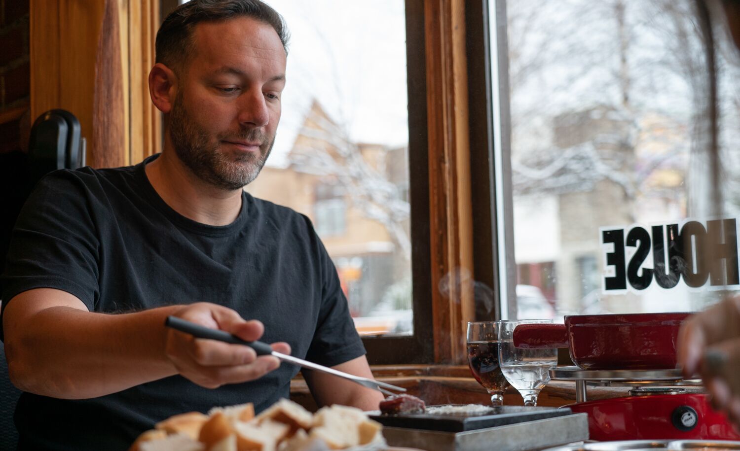 A man cooks a piece of meat on a griddle at his table at Grizzly House in Banff.