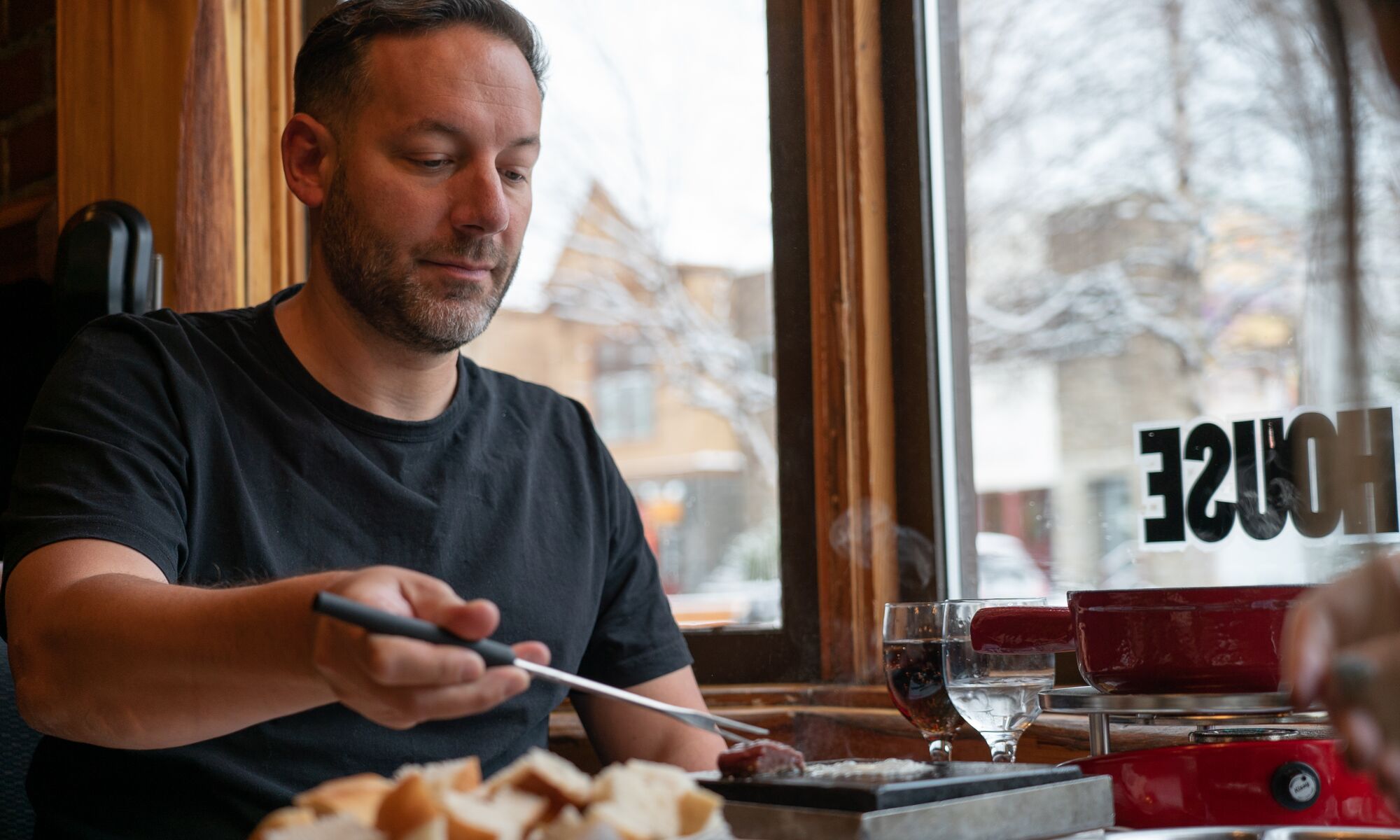 A man cooks a piece of meat on a griddle at his table at Grizzly House in Banff.