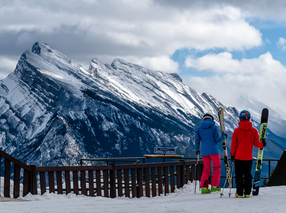 Two skiers standing at a view point at Mount Norquay looking at Mount Rundle in Banff national Park