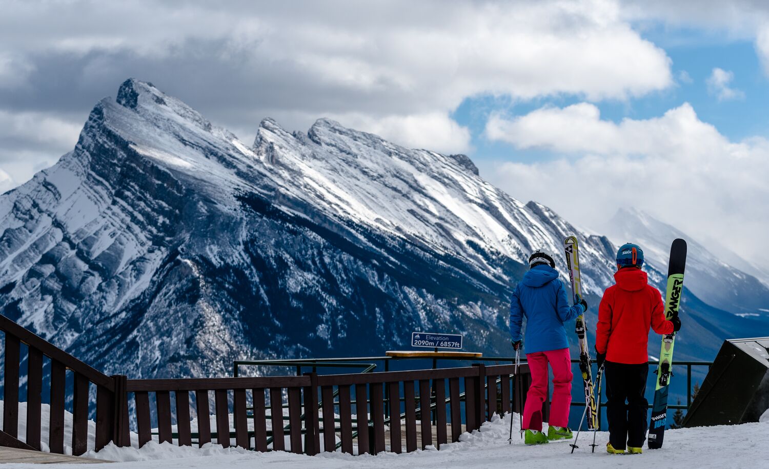 Two skiers standing at a view point at Mount Norquay looking at Mount Rundle in Banff national Park