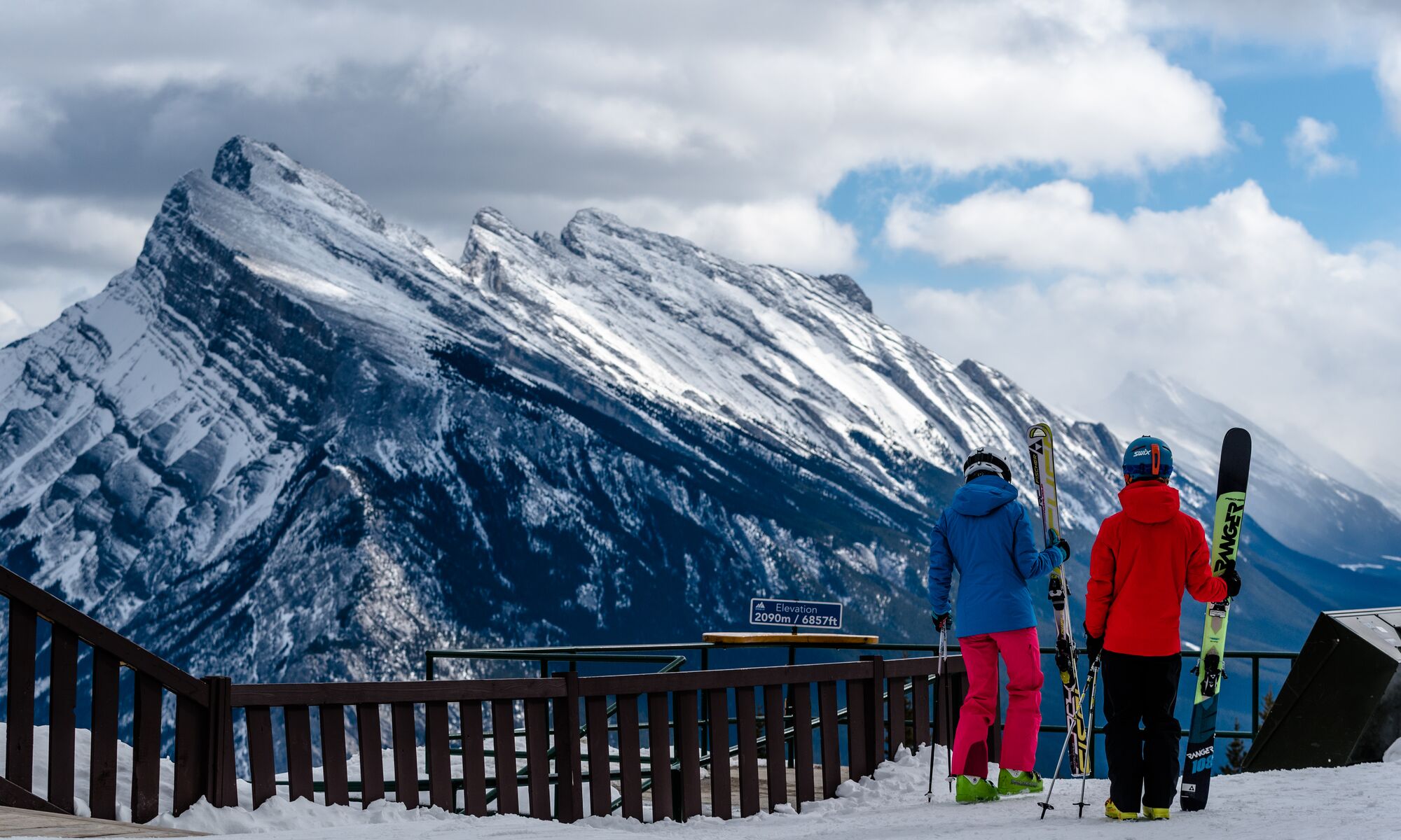 Two skiers standing at a view point at Mount Norquay looking at Mount Rundle in Banff national Park