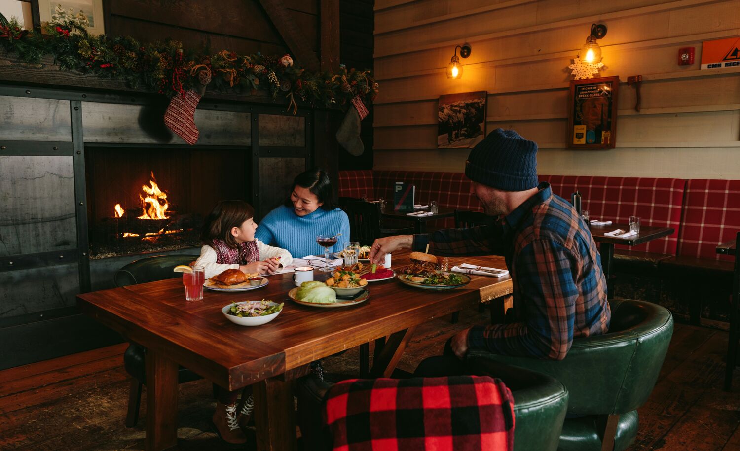 A family dines at Park Distillery with a fireplace behind them in Banff National Park.