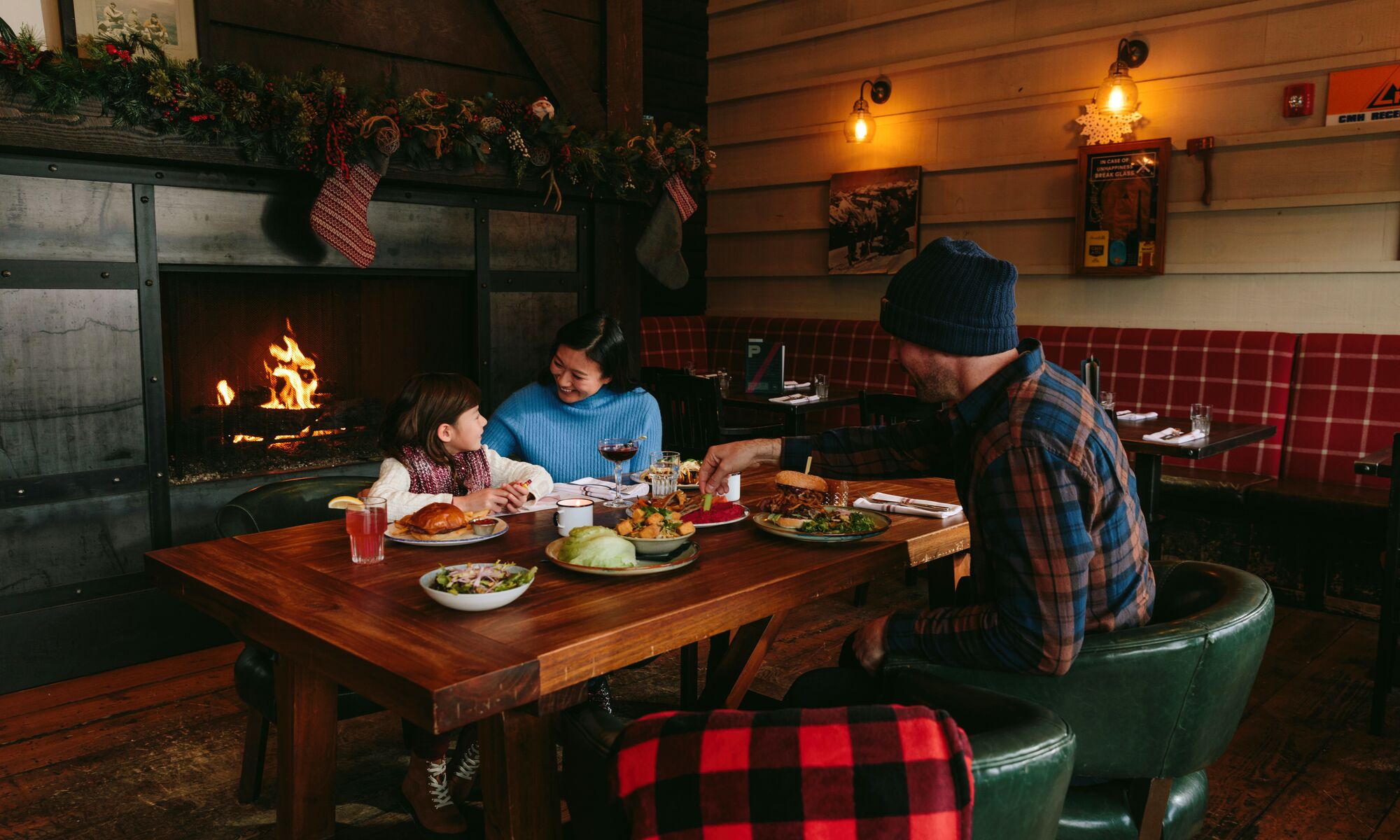 A family dines at Park Distillery with a fireplace behind them in Banff National Park.