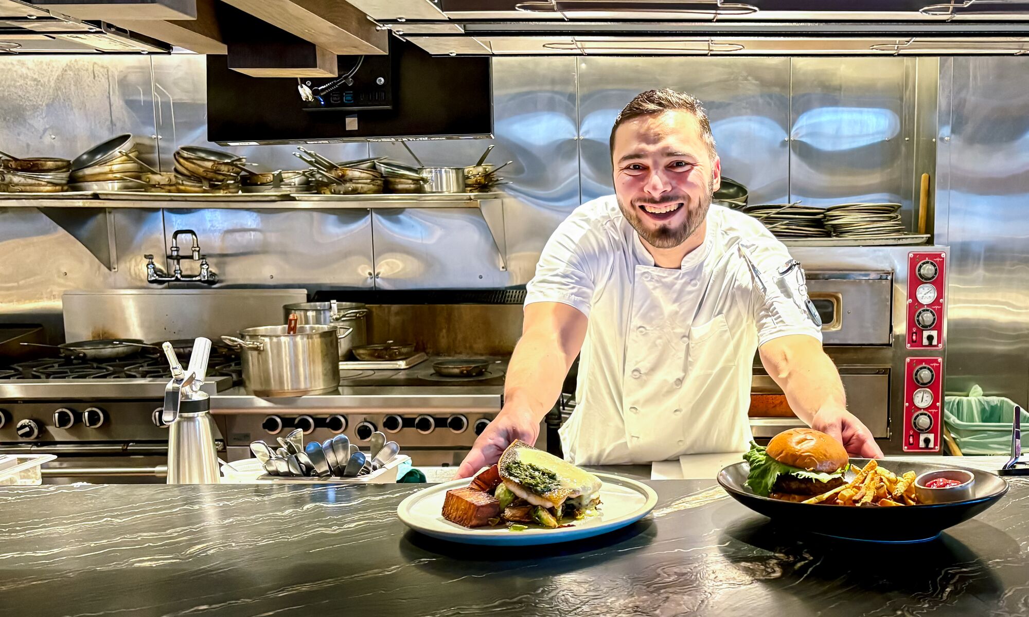 Head Chef of Good Folk Victor Bonilla slides two plates of food across a table in Banff.