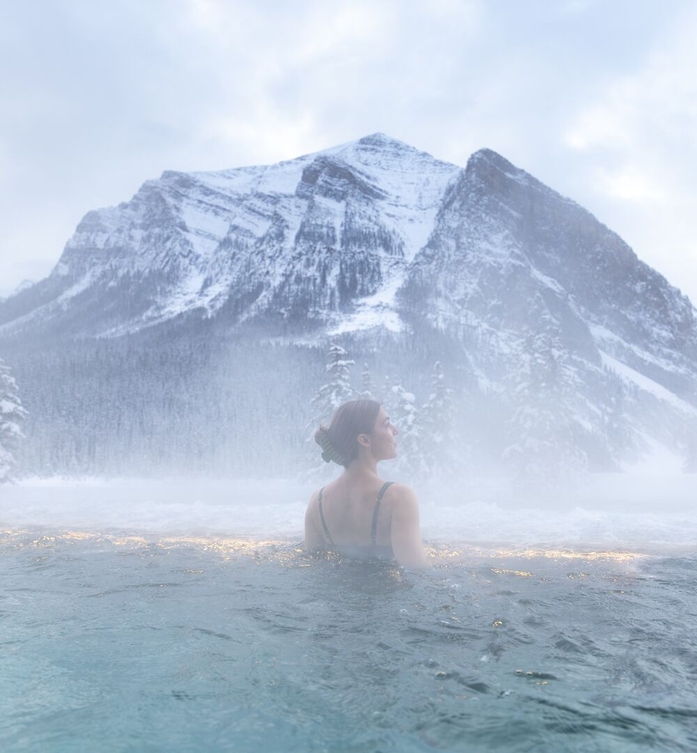Solo female at BASIN Glacial Waters outdoor hot pool during winter in Lake Louise