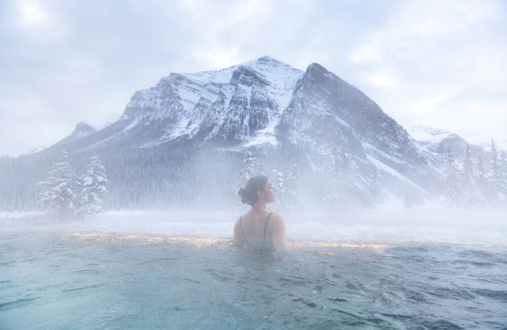 Solo female at BASIN Glacial Waters outdoor hot pool during winter in Lake Louise