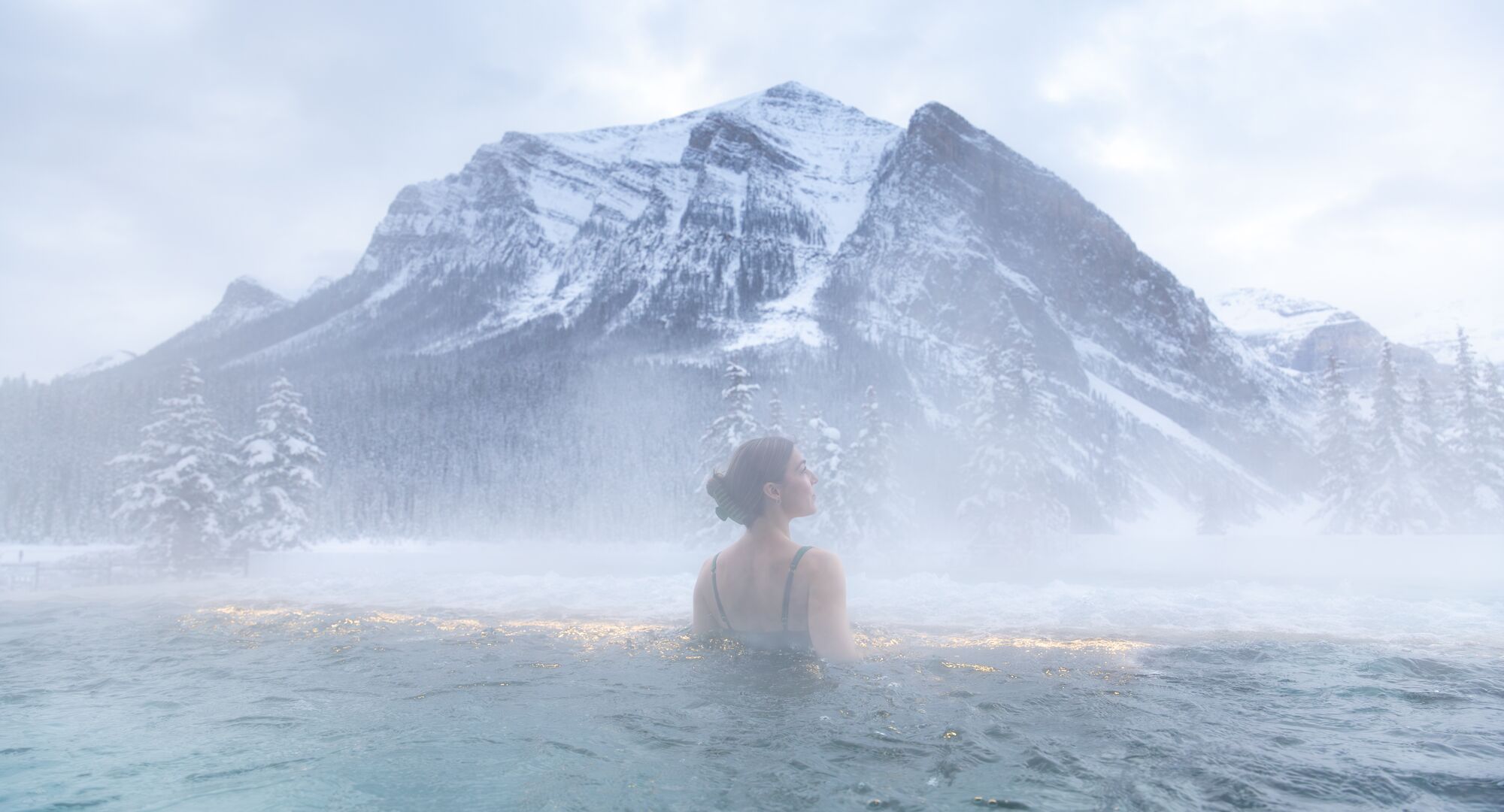 Solo female at BASIN Glacial Waters outdoor hot pool during winter in Lake Louise